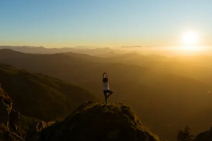 woman stretching on mountain top during sunrise
